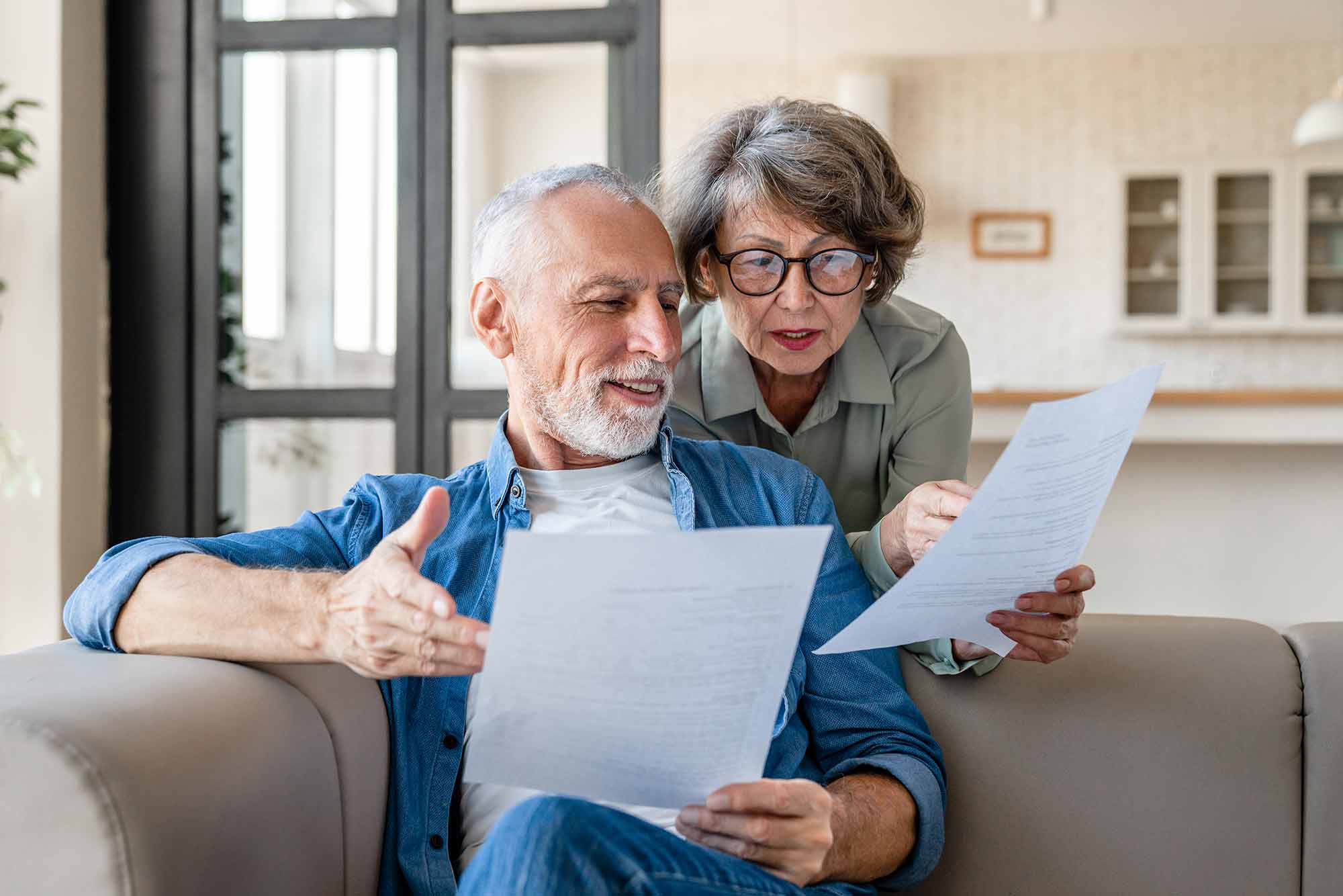 Couple on the couch reviewing financial documents together