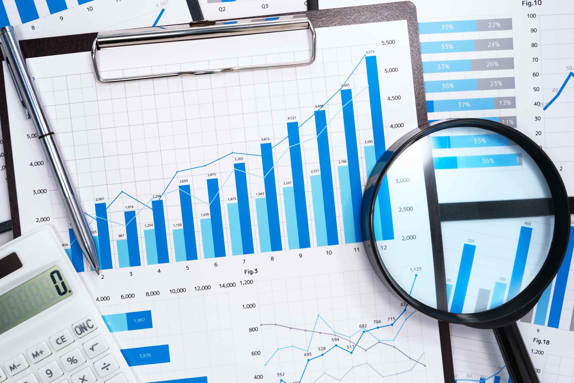Magnifying glass laying across papers with numbers and charts