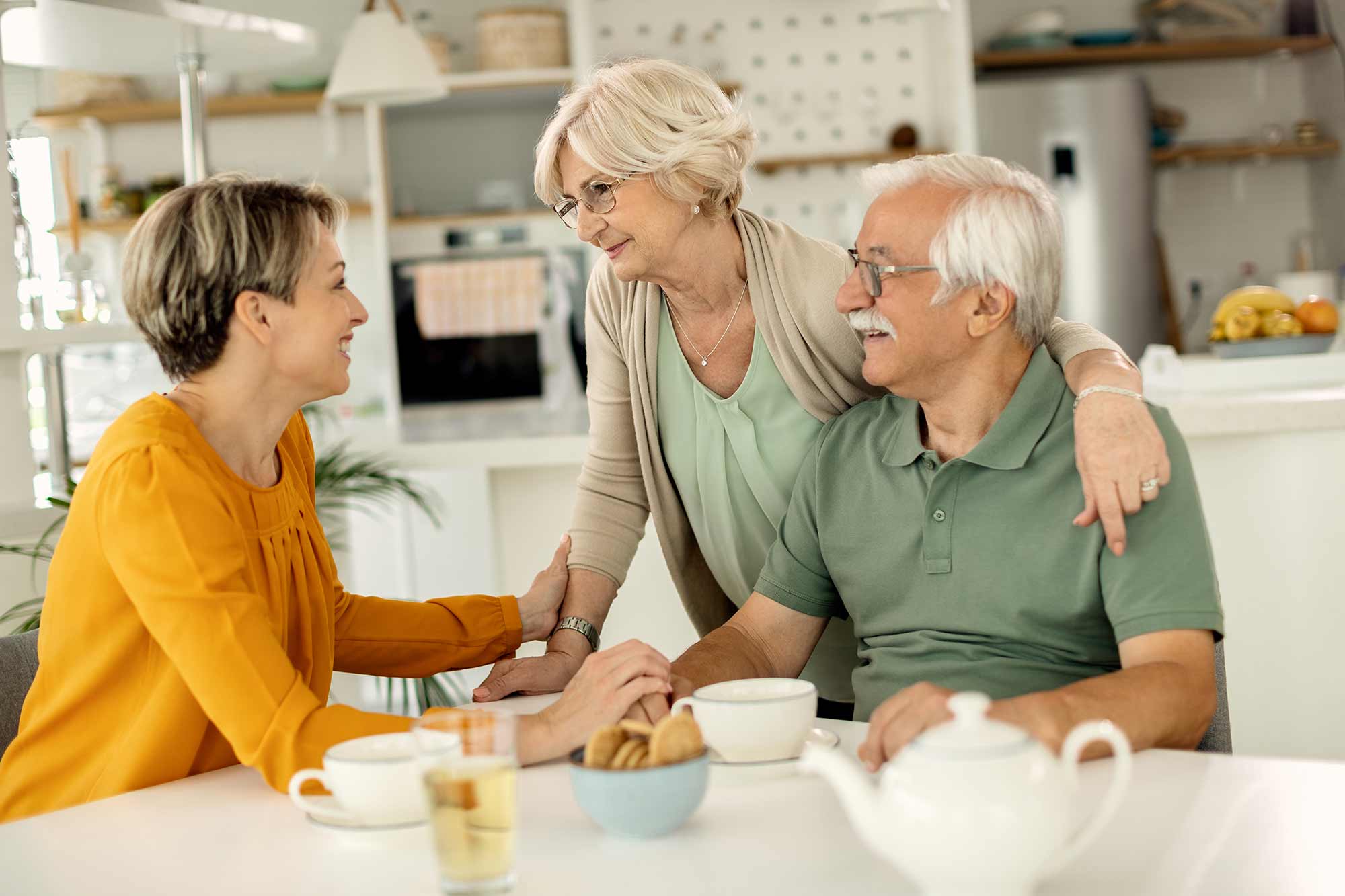 A woman talking with her parents at the kitchen table