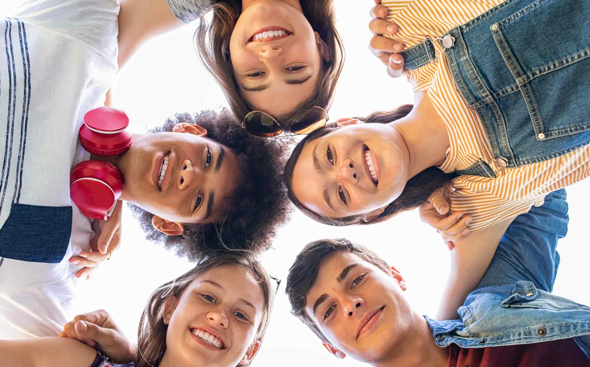A group of kids looking down at the camera and smiling