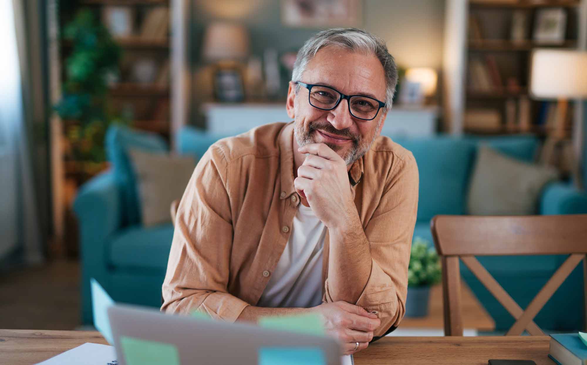Man with glasses at his desk smiling