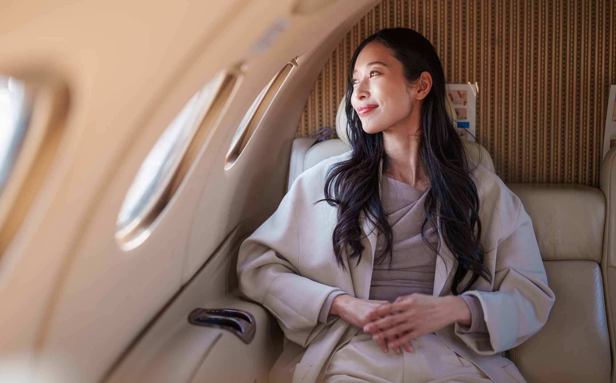 Woman in a private jet looking out the window and smiling