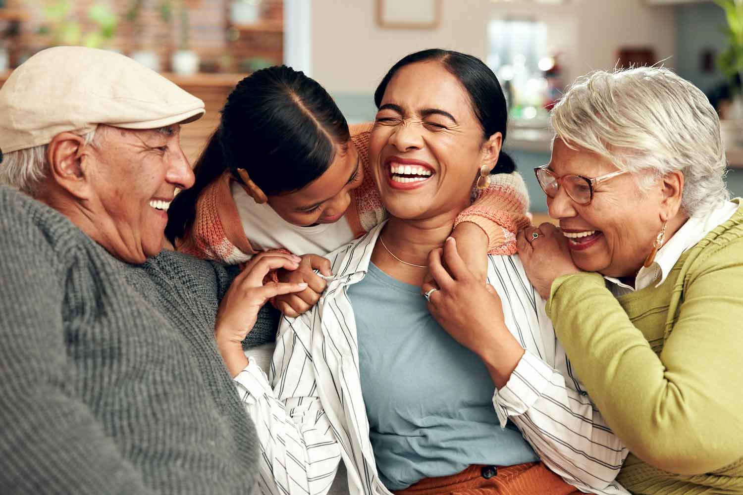 Three generations of a family laughing together on a living room couch