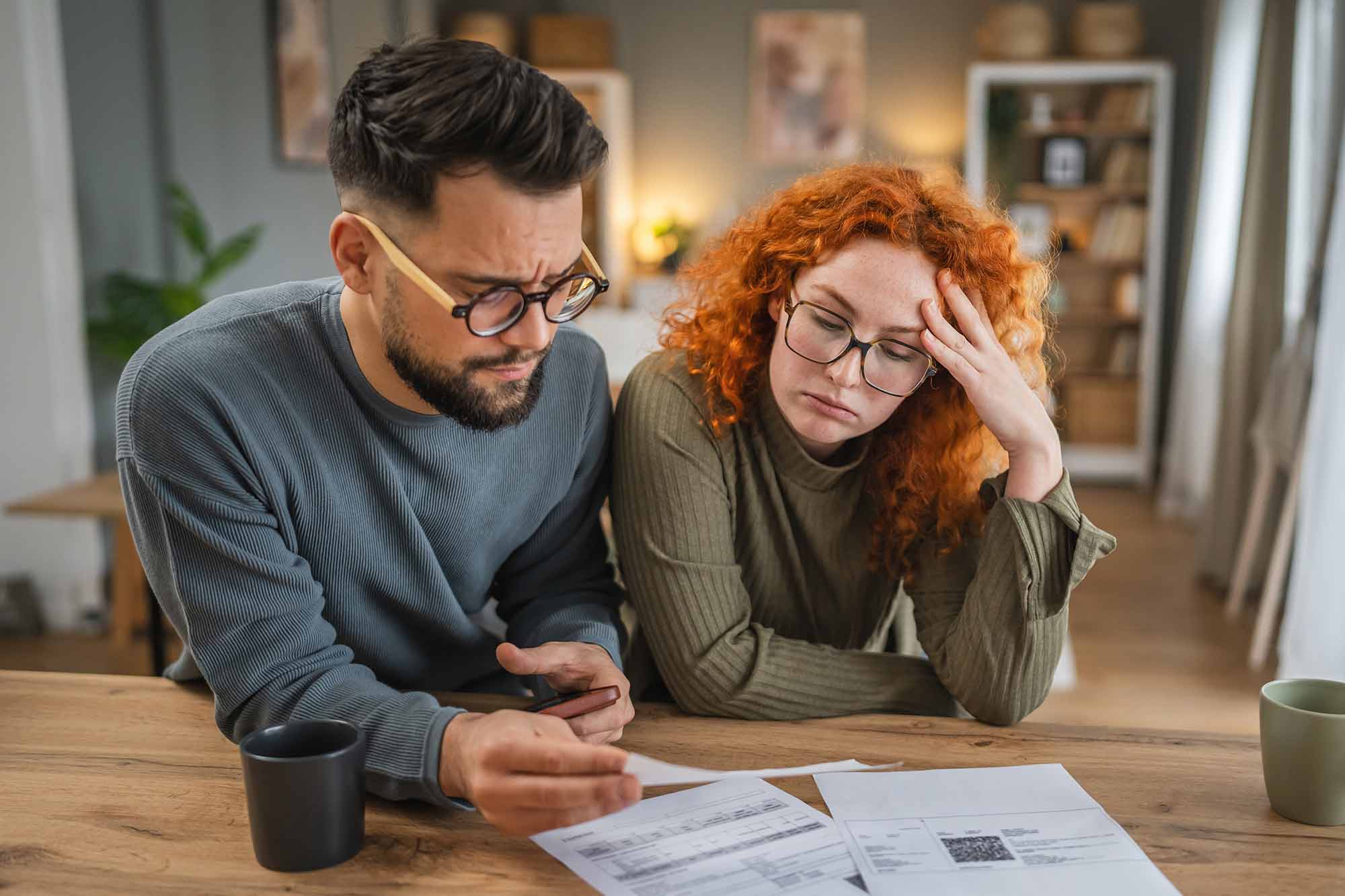 A couple in their thirties looking at bills and worrying