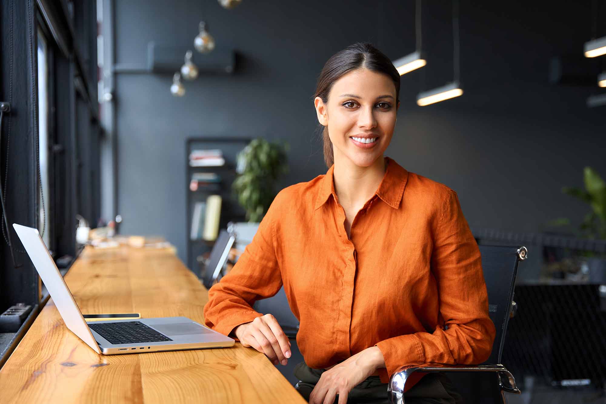 Woman sitting in a co-working space with her laptop smiling